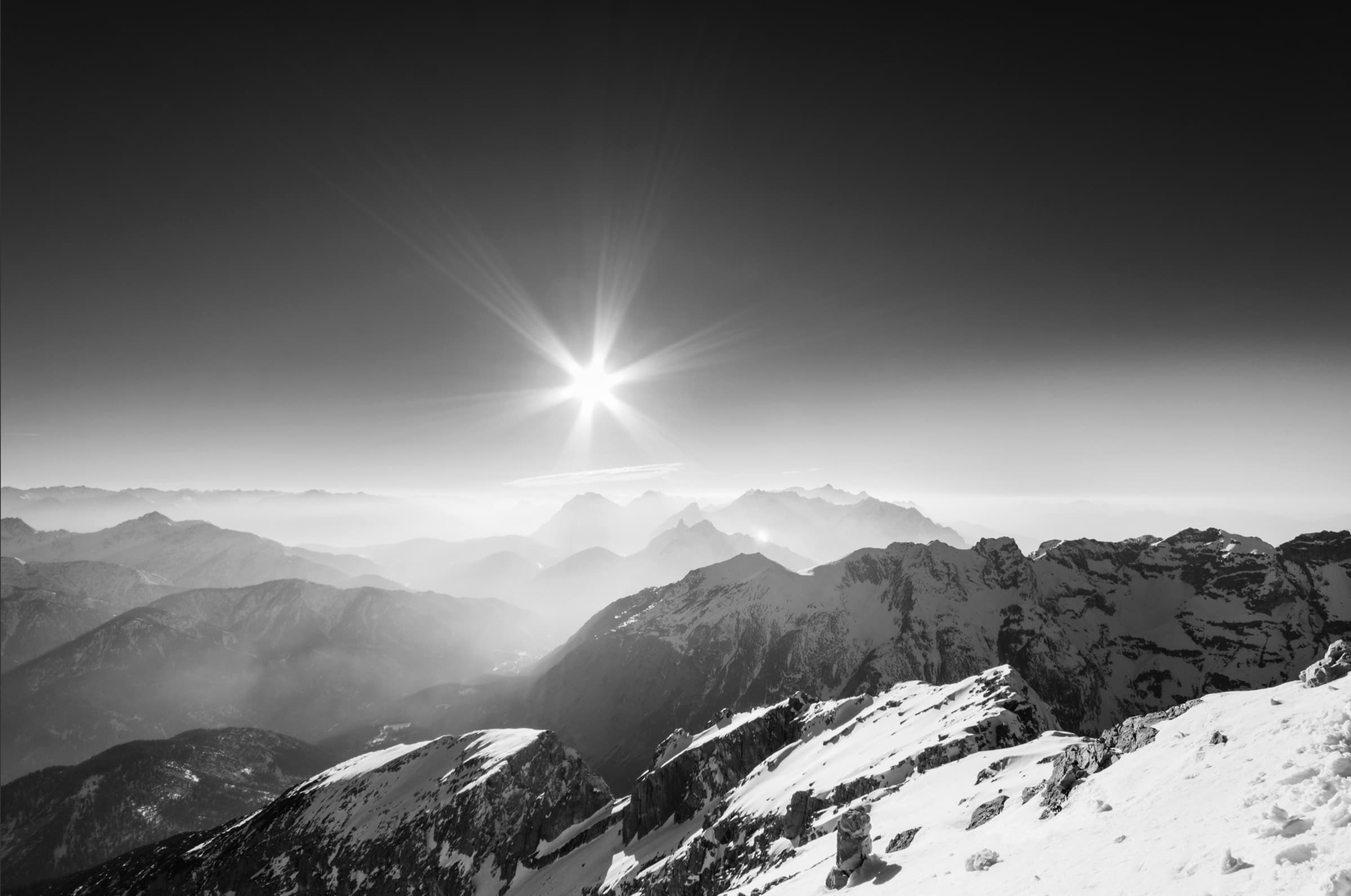 Blick über die verschneiten Gipfel der Alpen bei Gegenlicht